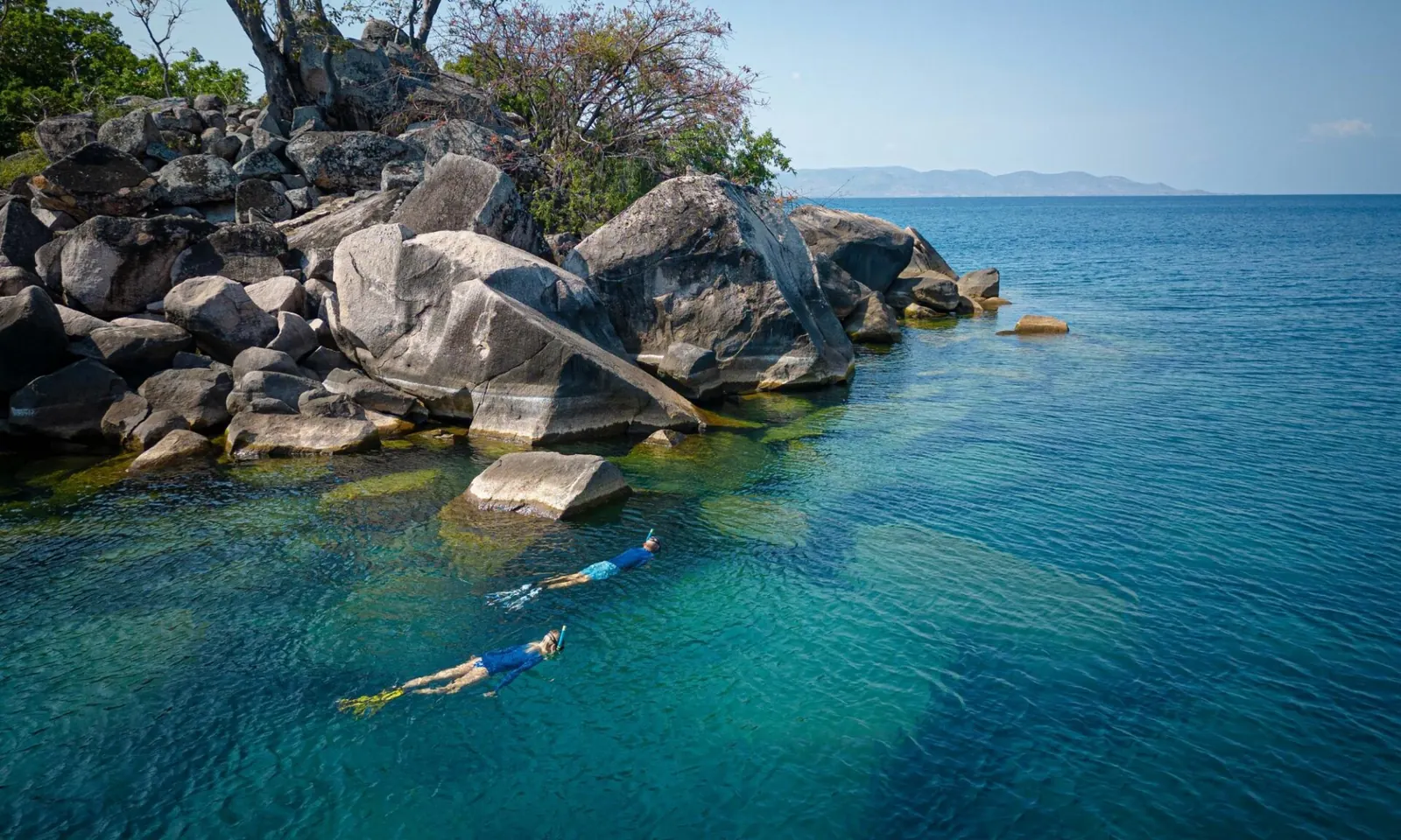 Snorkellers among granite boulders in the clear water of Lake Malawi